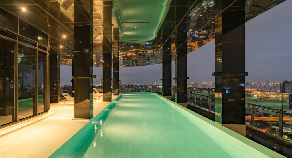 empty luxury swimming pool in hotel, condominium apartment, or resort. lights illuminated at night time. interior and architecture design decoration.